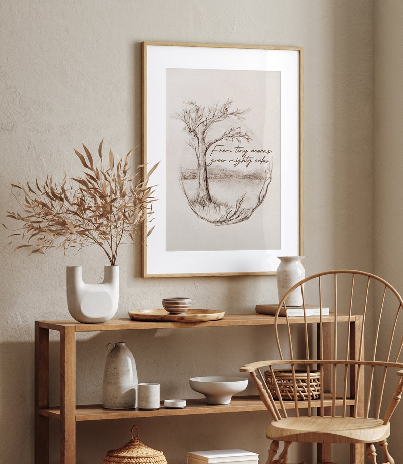 Puede incluir: Una impresi&oacute;n enmarcada con una ilustraci&oacute;n dibujada a mano de un &aacute;rbol con el texto "From tiny acorns grow mighty oaks". La impresi&oacute;n est&aacute; colgada en una pared sobre un estante de madera con art&iacute;culos decorativos.