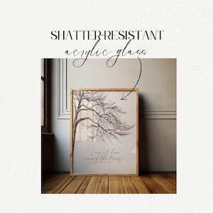 May include: A framed print with a black and white drawing of a tree with the quote "I am at home among the trees." by  R.W. Emerson. The frame is made of wood and has a light brown finish. The print is on shatter-resistant acrylic glass.