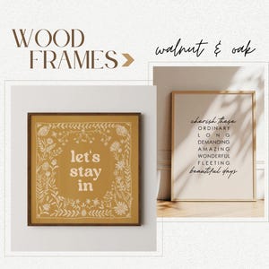 May include: Two framed prints with a mustard yellow background and white text. The first print says "let's stay in" and is surrounded by a white floral border. The second print says "cherish these ordinary long demanding amazing wonderful fleeting beautiful days". Both prints are in walnut and oak frames.