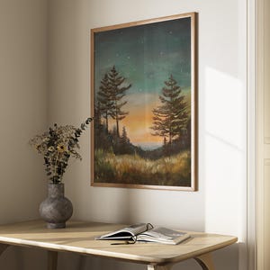May include: A framed painting of a forest scene at sunset with two pine trees in the foreground and a starry sky above. The painting is in a wooden frame and is hanging on a wall.