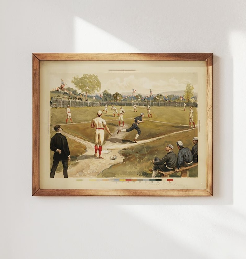 May include: A framed vintage baseball print. The artwork depicts a baseball game in progress, with players in period uniforms on a green field. The print is in a wooden frame, showcasing a classic sports theme.