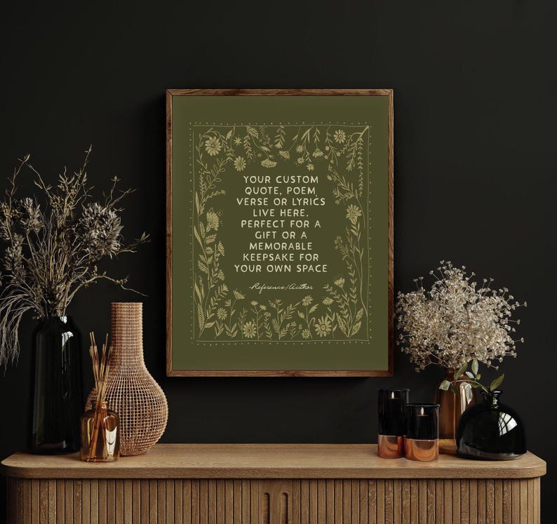 May include: A framed print with a green background and gold floral border. The text reads "YOUR CUSTOM QUOTE, POEM, VERSE OR LYRICS LIVE HERE. PERFECT FOR A GIFT OR A MEMORABLE KEEPSAKE FOR YOUR OWN SPACE." The print is displayed on a wooden cabinet.