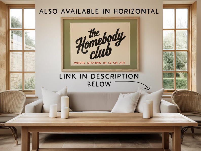 K&ouml;nnte beinhalten: Ein gerahmtes Poster mit dem Text "the Homebody club" in schwarzer Schrift, mit den Worten "WHERE STAYING IN IS AN ART" darunter. Das Poster befindet sich &uuml;ber einem hellen Sofa mit wei&szlig;en Kissen und einem Holztisch.