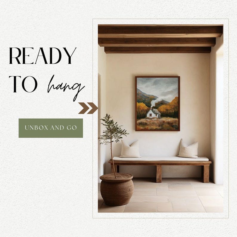 May include: A framed landscape painting of a small white house with a chimney in a forest setting. The painting is hanging on a white wall in a room with wooden beams and a wooden bench. The painting is ready to hang.