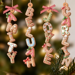 May include: Gingerbread cookie decorations spelling out "AMITY", "BELUAH", "JOYCE", and "CARLIN". Each letter is decorated with icing and festive details, strung with twine and red ribbon bows, ideal for Christmas decorations.