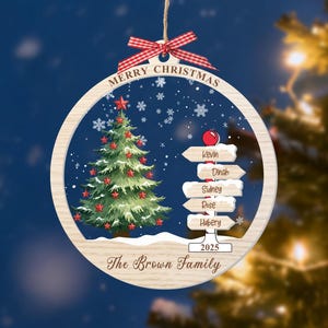 May include: A round wooden Christmas ornament featuring a green tree with red stars, a signpost with the names Kevin, Dinah, Sidney, Rose, and Hubery, and the text Merry Christmas, 2025, and The Brown Family, topped with a red gingham bow.