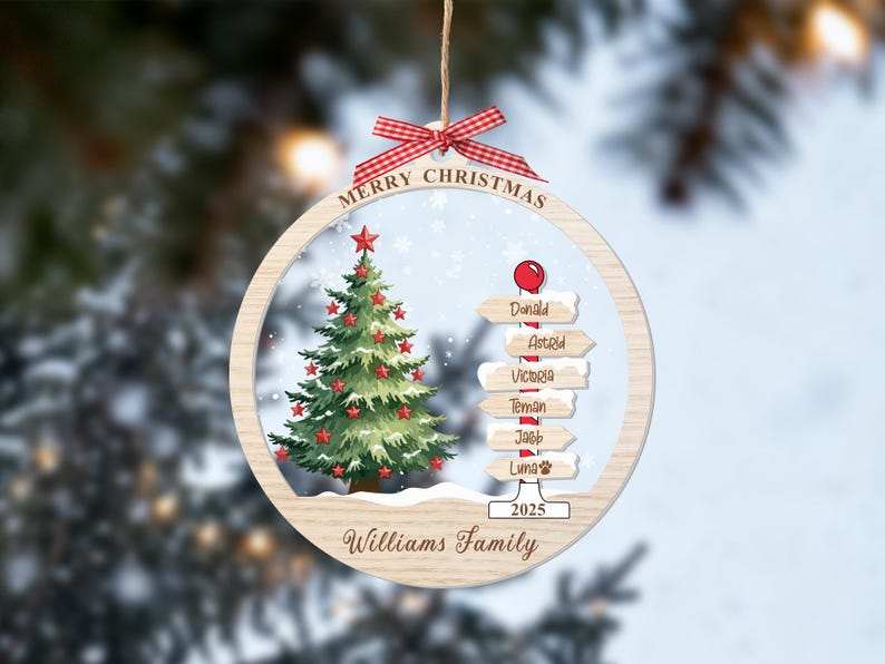 May include: A round wooden Christmas ornament featuring a green tree with red stars, a signpost with the names Donald, Astrid, Victoria, Teman, Jacob, and Luna, the text Merry Christmas, 2025, and Williams Family, topped with a red gingham bow.