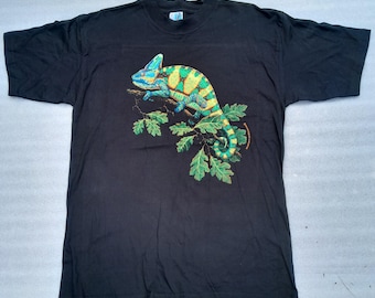 Może przedstawiać: Czarny T-shirt z zielonym i żółtym kameleonem na gałęzi z zielonymi liśćmi.