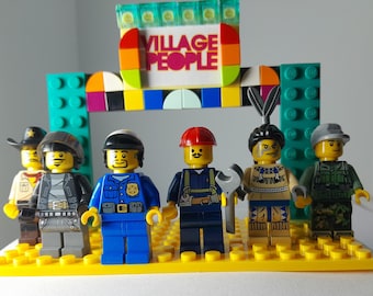 Könnte beinhalten: Ein Set aus sechs Kunststoff-Klemmbaustein-Minifiguren auf einer gelben Grundplatte vor einem bunten Torbogen mit einem Schild, auf dem VILLAGE PEOPLE steht. Die Figuren stellen verschiedene Charaktere mit unterschiedlichen Outfits dar.