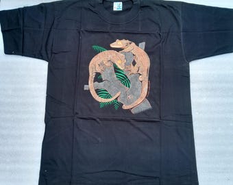 Może przedstawiać: Czarny T-shirt z nadrukiem graficznym dwóch gekonów na gałęzi z zielonymi liśćmi.