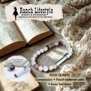 May include: A rose quartz bead bracelet with a silver secret message cylinder. The bracelet is displayed with an open book and a soft, textured background. The text reads "Ranch Lifestyle Jewelry & Accessories Inspired by the Spirit of the Wild West."