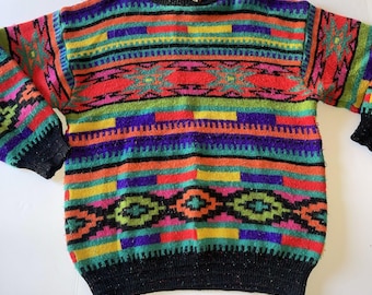Puede incluir: Un suéter colorido con estampado y cuello redondo. El suéter presenta rayas horizontales en rojo, naranja, amarillo, verde, morado y negro, con diseños geométricos. Los puños y el cuello son negros.