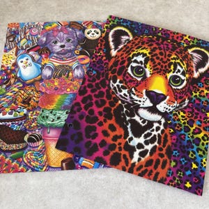 May include: Two colorful notebooks. One features a purple dog with a bow, surrounded by sweets and ice cream. The other has a leopard with a vibrant, rainbow-colored spotted pattern. The notebooks have a spiral binding.