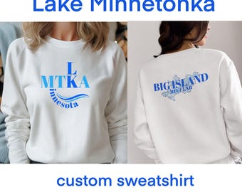 May include: White sweatshirt with a blue and white graphic design on the front that says "L MTKA Minnesota" and a blue and white graphic design on the back that says "Big Island Regatta".