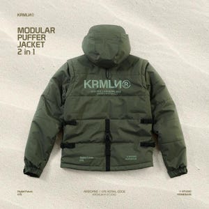 May include: An olive green modular puffer jacket with a hood. The jacket has the text "KRMLU" and "MODULAR PUFFER JACKET 2 in 1" printed on it. It features black buckles and straps, and the text "Digital Future 078" is also visible.