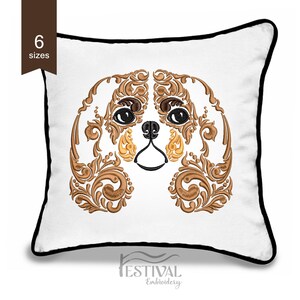 May include: A white pillow with a black border features an embroidered design of a Cavalier King Charles Spaniel dog's face. The dog's face is made up of intricate floral patterns in shades of brown and gold.