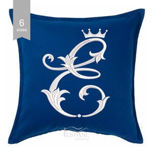 May include: A royal blue cushion featuring a white embroidered letter "E" and a crown. The letter is decorated with floral patterns. The cushion has the text "6 sizes" in the upper left corner.
