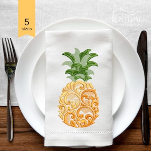 Puede incluir: Diseño de piña bordado en una toalla de cocina blanca. La piña es amarilla y verde con un patrón floral detallado.