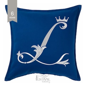 Puede incluir: Un cojín cuadrado azul real con una gran letra "L" plateada bordada, coronada con una corona. La letra tiene adornos ornamentados. El cojín tiene el texto "6 tamaños" en un rectángulo gris en la esquina superior izquierda. El texto "FESTIVAL Embroidery" está en la parte inferior.