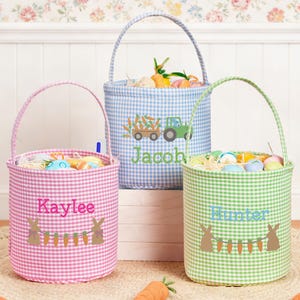 May include: Three gingham Easter baskets in pink, blue, and green, each with a handle and filled with Easter eggs and decorative grass. The pink basket says "Kaylee", the blue basket says "Jacob", and the green basket says "Hunter".
