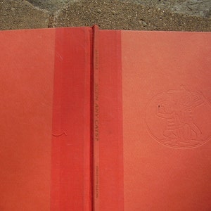 May include: A red hardcover book with the title "Seen Any Cats?" by  Greenwillow. The book cover features a black and white illustration of two people.