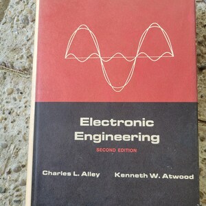 May include: A red and black book titled "Electronic Engineering" with the words "Second Edition" printed below the title. The authors' names are listed below the edition: "Charles L. Alley" and "Kenneth W. Atwood". The cover features a white sine wave graphic.