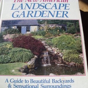 May include: The cover of a book titled "The New American Landscape Gardener" features a vibrant image of a backyard garden with a waterfall, pond, and lush greenery. The book's subtitle reads, "A Guide to Beautiful Backyards & Sensational Surroundings."