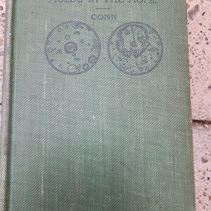 May include: A vintage book titled "Bacteria, Yeasts, and Molds in the Home" by Conn. The cover is a muted green with the title in dark text. Two circular illustrations of microorganisms are featured below the title.