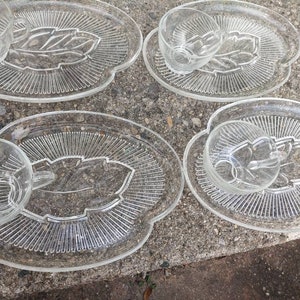 May include: Set of four clear glass serving dishes with a leaf design. Each dish has a matching cup.