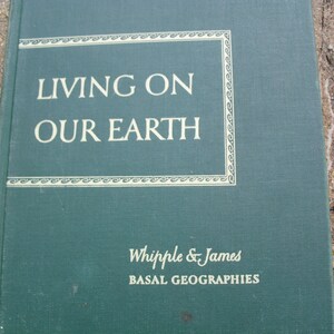 Puede incluir: Un libro verde con el título "Living on Our Earth" en texto blanco. El libro forma parte de la serie "Basal Geographies" de Whipple & James.