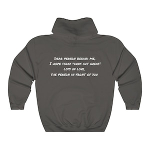 May include: Dark gray hooded sweatshirt with white text on the back. The text reads: "DEAR PERSON BEHIND ME, I HOPE TODAY TURNS OUT GREAT! LOTS OF LOVE, THE PERSON IN FRONT OF YOU."