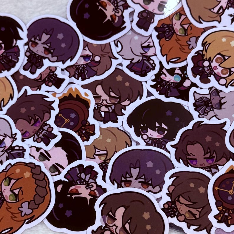 May include: A collection of colorful cartoon character stickers featuring various designs and expressions. The stickers are printed on white paper and have a glossy finish.