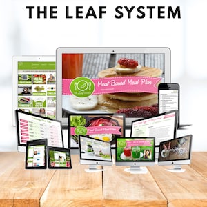 May include: A collection of digital devices displaying the text "THE LEAF SYSTEM" and "Meat Based Meal Plan". The devices include laptops, tablets, and smartphones, showcasing meal plans and related content. The background is a wooden surface.