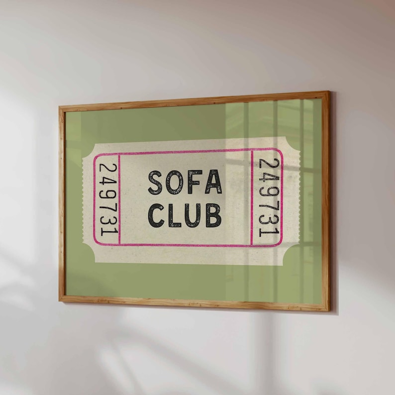 May include: A framed print featuring a vintage-style ticket design. The ticket has a light green background with the words "SOFA CLUB" in bold black letters. The ticket's edges are outlined in pink, with the number "249731" printed on each end.