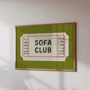 May include: A framed print featuring a vintage-style ticket design. The ticket has the words "SOFA CLUB" in bold black letters, with the number "249731" on each side. The background is a solid green, and the frame is a natural wood color.