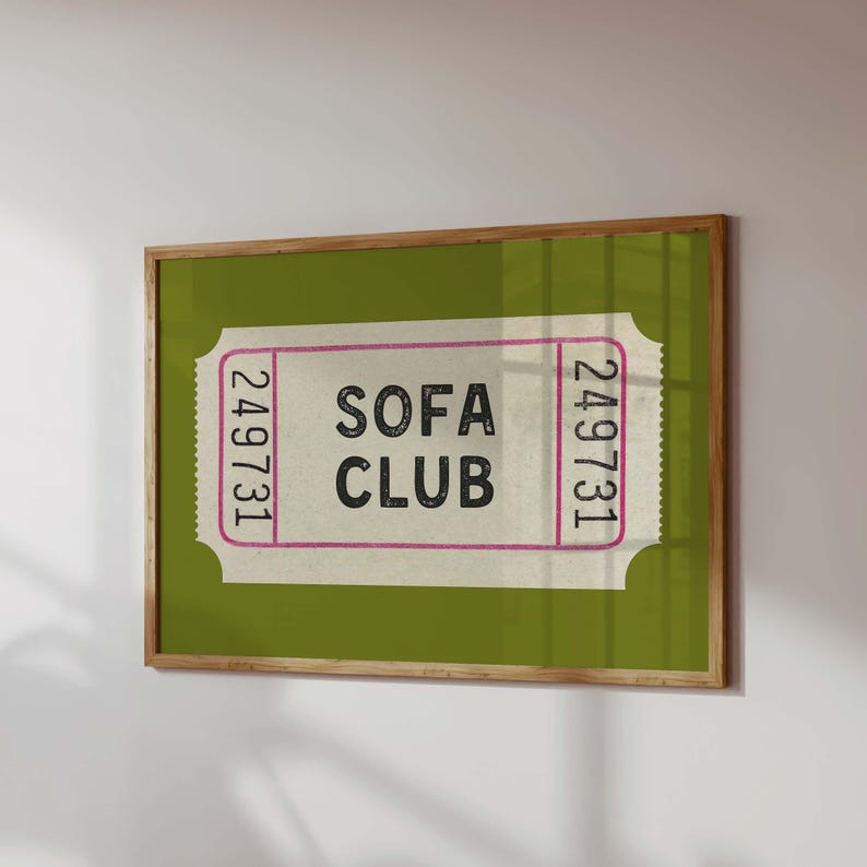 May include: A framed print featuring a vintage-style ticket design. The ticket has the words "SOFA CLUB" in bold black letters, with the number "249731" on each side. The background is a solid green, and the frame is a natural wood color.