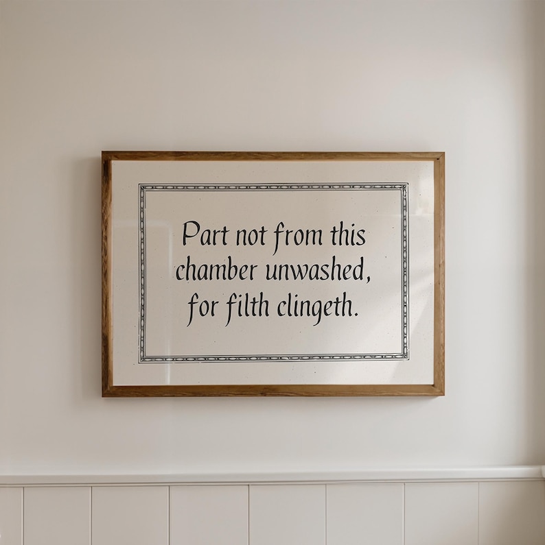 Funny printable bathroom wall art that says 'part not from this chamber unwashed, for filth clingeth' in black medieval font with medieval style border on a beige background. Displayed in a horizontal wooden frame hanging on a neutral wall.