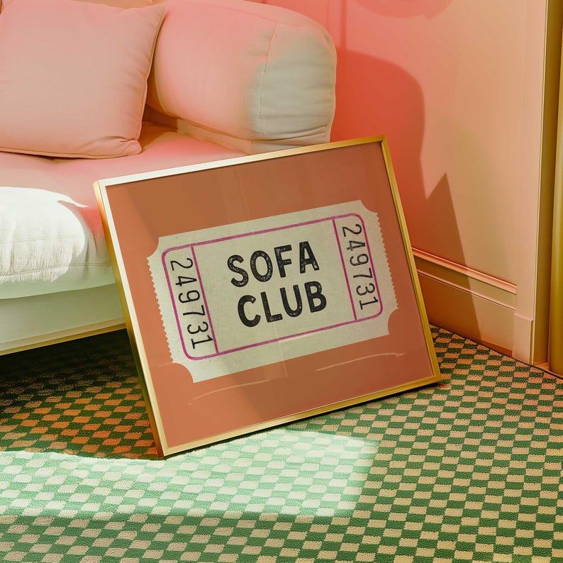May include: A framed print with the words "SOFA CLUB" on a ticket design. The print has a gold frame and is set against a peach-colored background. The print is on a green and white checkered floor.