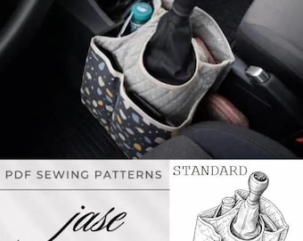 May include: A fabric car console organiser featuring a dark blue exterior with a multi-coloured abstract pattern and a light grey quilted interior. The organiser fits around a manual gear shift lever and includes multiple storage pockets.