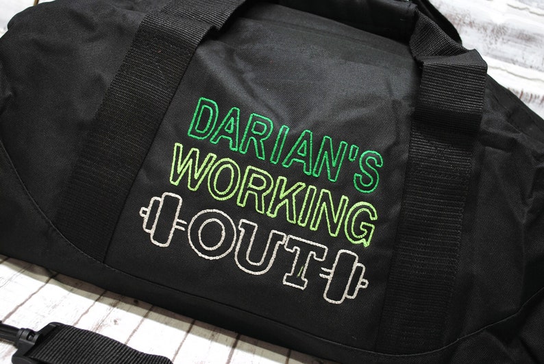 May include: Black duffel bag with a green and white embroidered design that says "Darian's Working Out" with a dumbbell on each side of the word "Out".