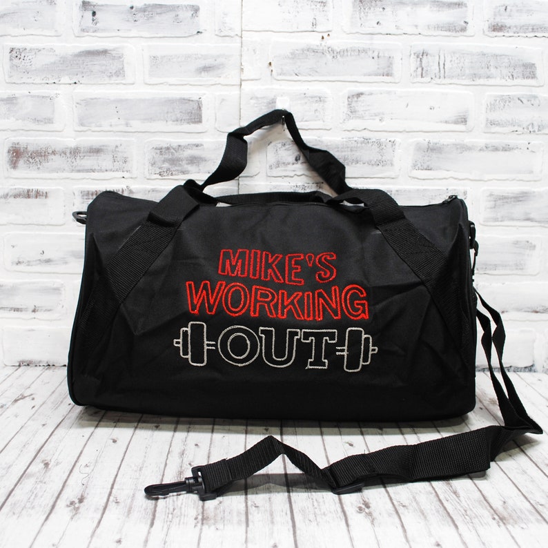 May include: Black duffel bag with a red embroidered design that says "Mike's Working Out" with a dumbbell graphic on either side of the word "Out".