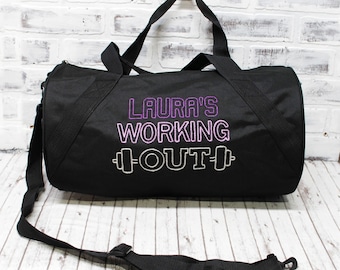 May include: Black duffel bag with a purple and white embroidered design that says "Laura's Working Out" with a dumbbell graphic on either side of the word "Out".