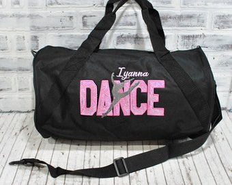 Puede incluir: Bolsa de deporte negra con un diseño de "DANCE" en purpurina rosa y plata y el nombre "Iyanna" bordado.