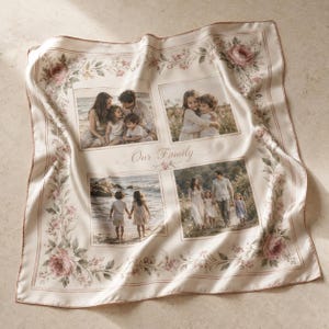 May include: A square cream-coloured satin scarf featuring a floral border with pink roses and green leaves. The centre displays four distinct family photographs arranged in a grid, with the cursive text Our Family printed in the middle.