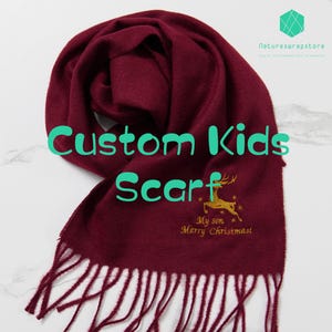 May include: Burgundy red custom kids scarf with a gold embroidered reindeer and the text "My son Merry Christmas".