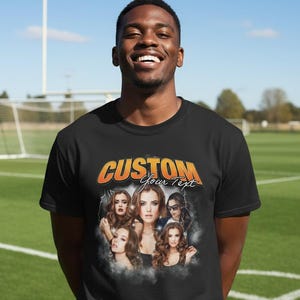 Peut inclure: T-shirt noir avec un motif graphique portant le texte "CUSTOM Your Text" en orange et jaune. Le motif comprend des images de cinq femmes. La personne portant le t-shirt sourit.