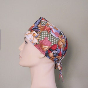 May include: A colorful surgical scrub hat with a teddy bear and other animal print. The hat has a green and white checkered pattern and is tied at the back with a long red and white string.