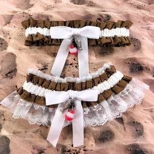 May include: Two brown and white garter belts with white satin bows and a charm. The charms are a silver fish and a red and white bobber.