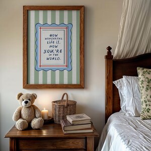 A vintage-inspired How Wonderful Life Is Now You’re In the World nursery print designed in soft sage green with playful stripes and a wavy frame. Perfect as kids wall art, playroom wall art, or part of a whimsical circus nursery theme. This timeless design brings warmth and storybook charm to baby rooms and makes a thoughtful gift for new parents. A beautiful piece of sage green nursery art for classic, character-filled interiors.