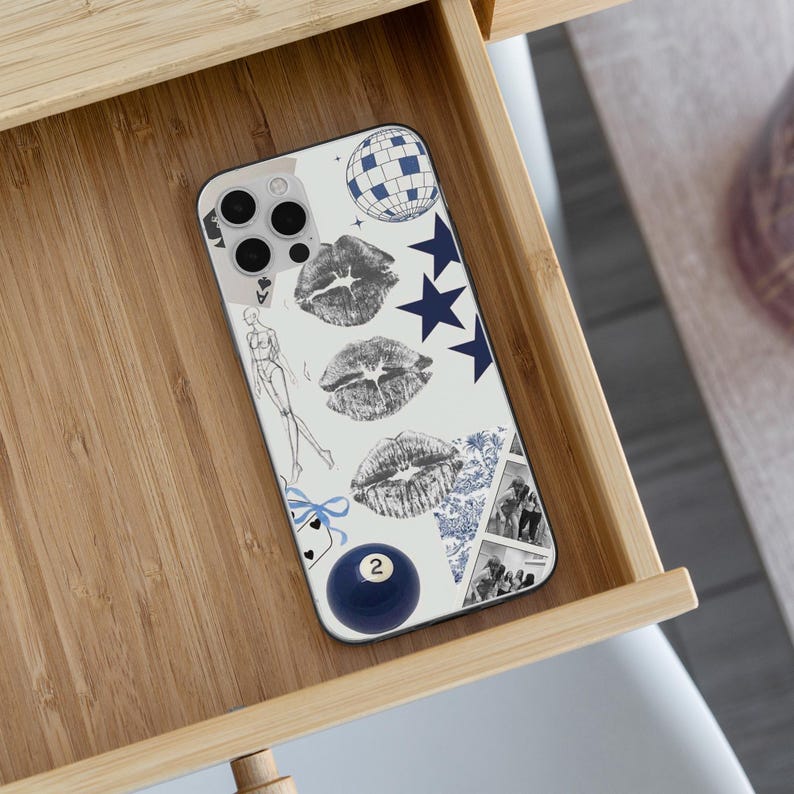 May include: A white phone case with a collage design featuring a disco ball, navy blue stars, and three sets of gray lipstick prints. Additional elements include a fashion sketch, a blue billiard ball with the number 2, and a blue and white patterned design.